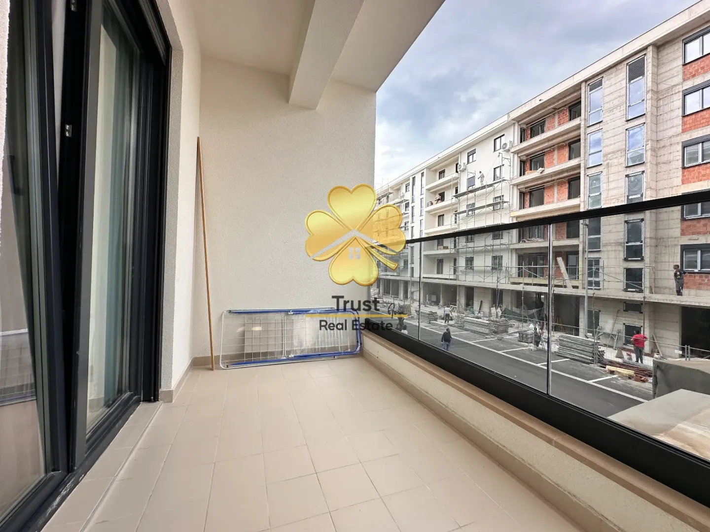 Spacious tiled terrace with a view of a building under construction.