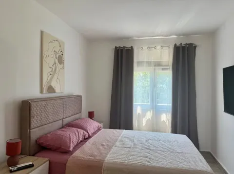 Uređena spavaća soba sa bračnim krevetom, umjetničkom slikom i prozorom sa tamnim zavjesama. - image 4