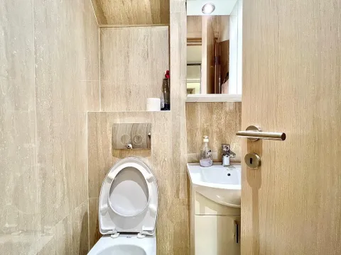A small bathroom with a toilet and a sink. - image 3
