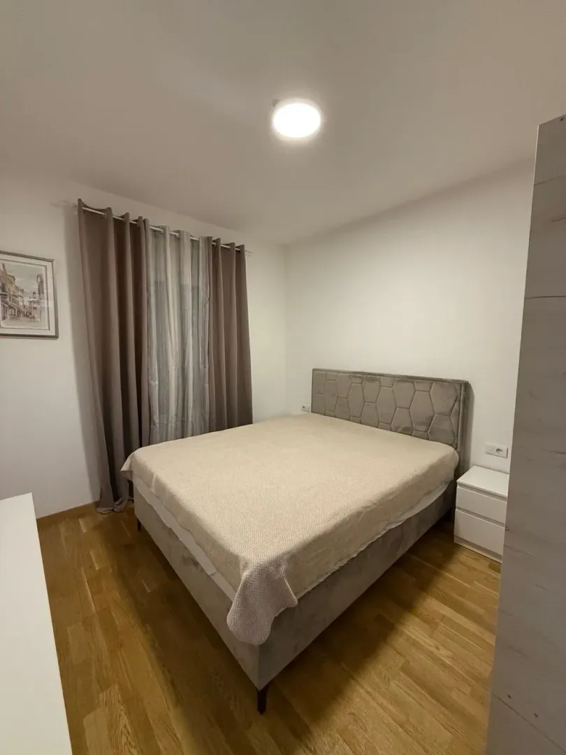 Furnished bedroom with a double bed, wardrobe, and wooden flooring.