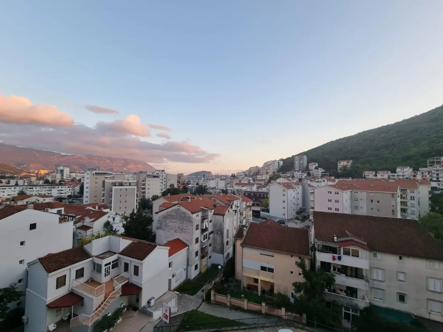Pogled na grad sa brdima i planinama u pozadini.