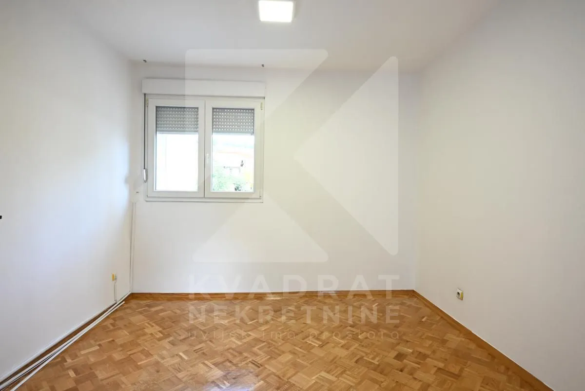 Empty room with white walls and parquet flooring.