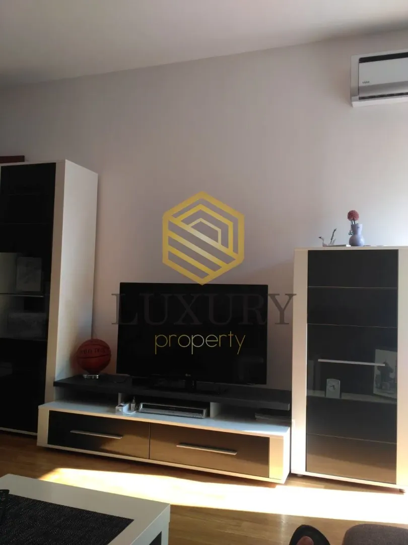 Dnevna soba sa TV komodom i namještajem.