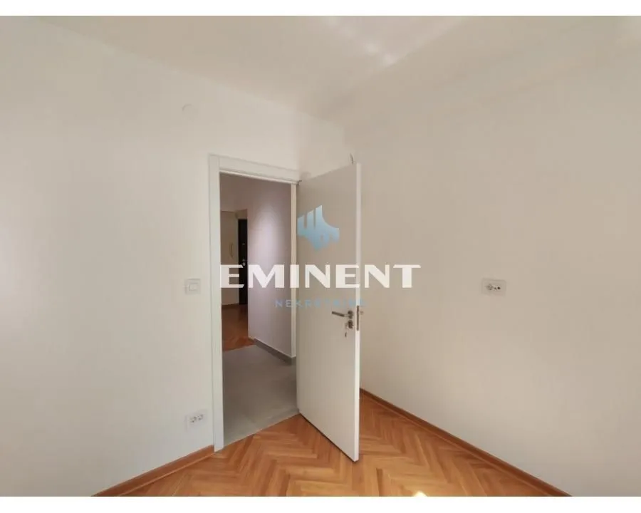 Empty room with parquet flooring and an open door.
