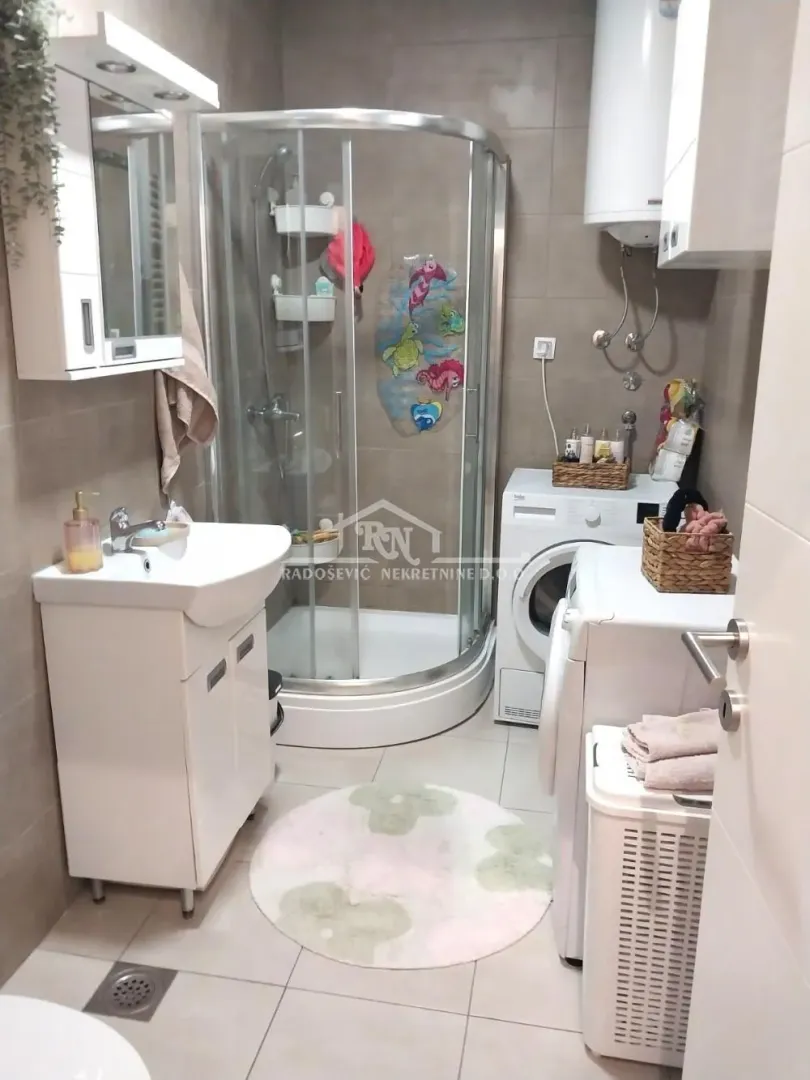 Bathroom equipped with a shower cabin, washbasin, and washing machine.