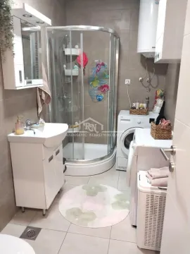 Bathroom equipped with a shower cabin, washbasin, and washing machine. - image 8