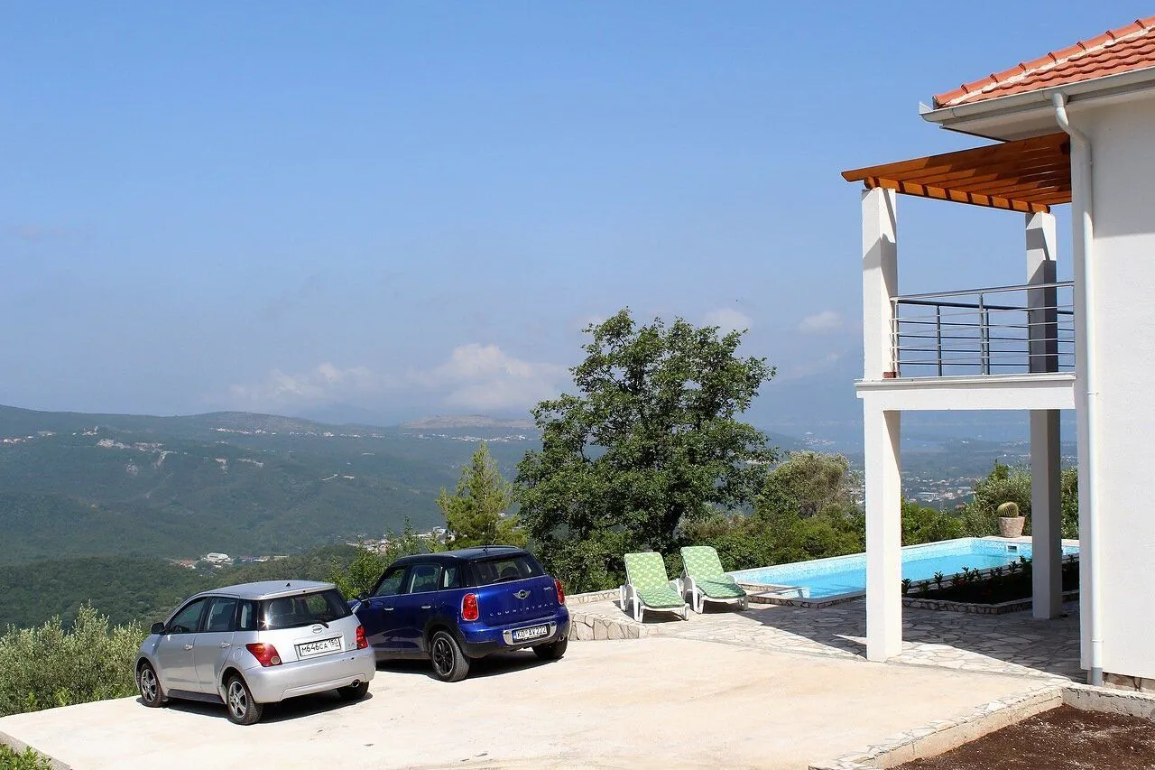 Exterior of the house with a swimming pool, parking space, and nature view.