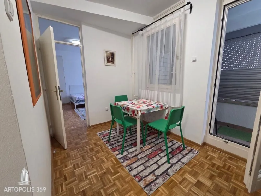 Manja trpezarija sa stolom i zelenim stolicama.