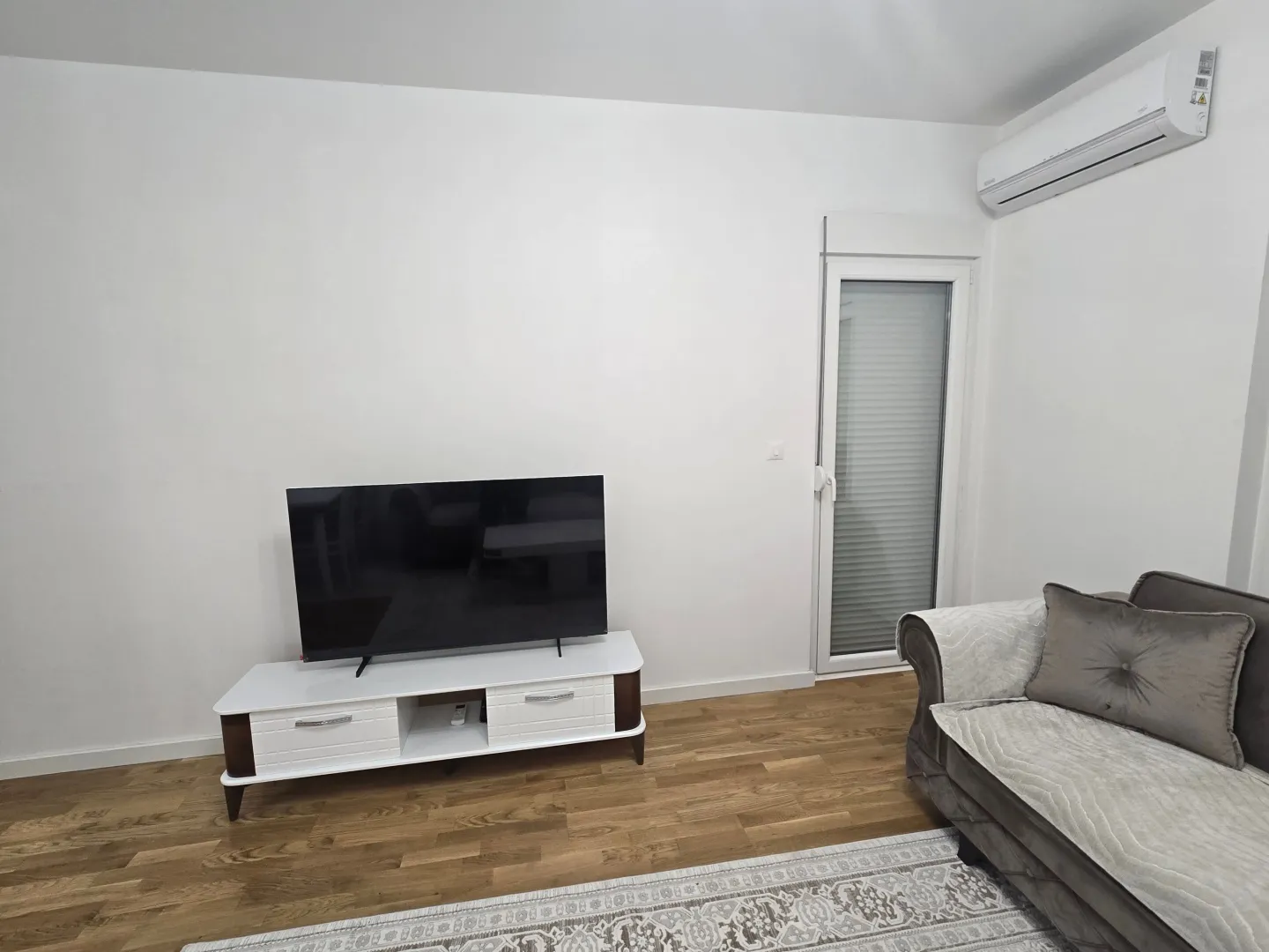 Living room with a sofa, TV, and air conditioning unit.