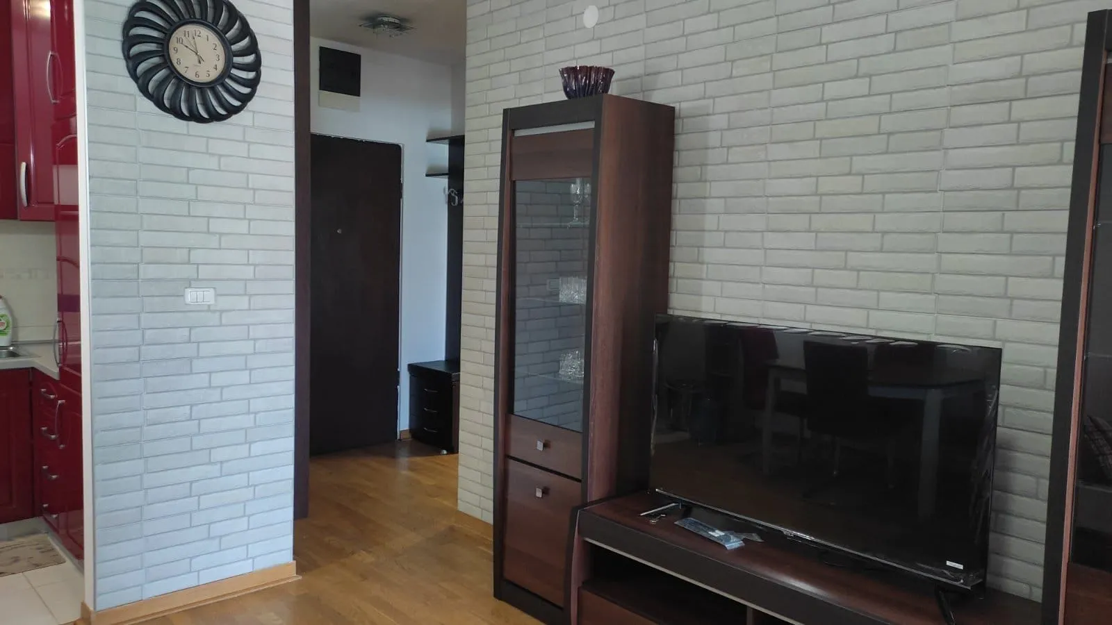 Dnevni boravak sa TV komodom i zidom obloženim dekorativnom ciglom.