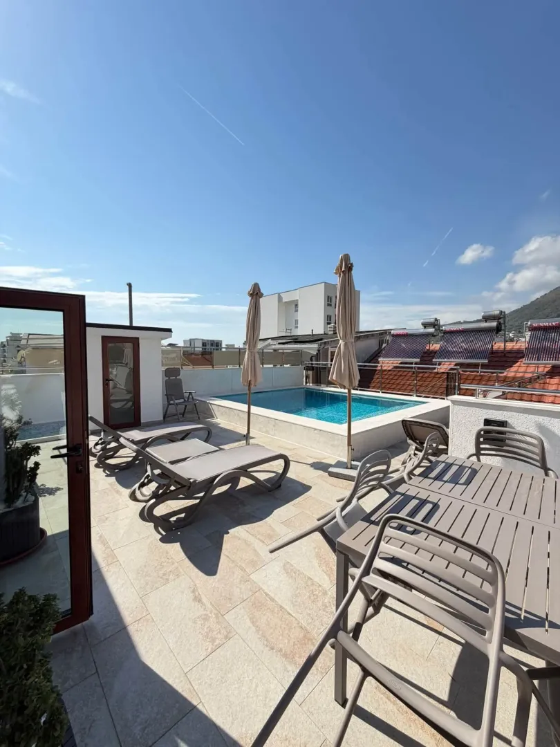 Roof terrace with a swimming pool, sun loungers, and seating furniture.