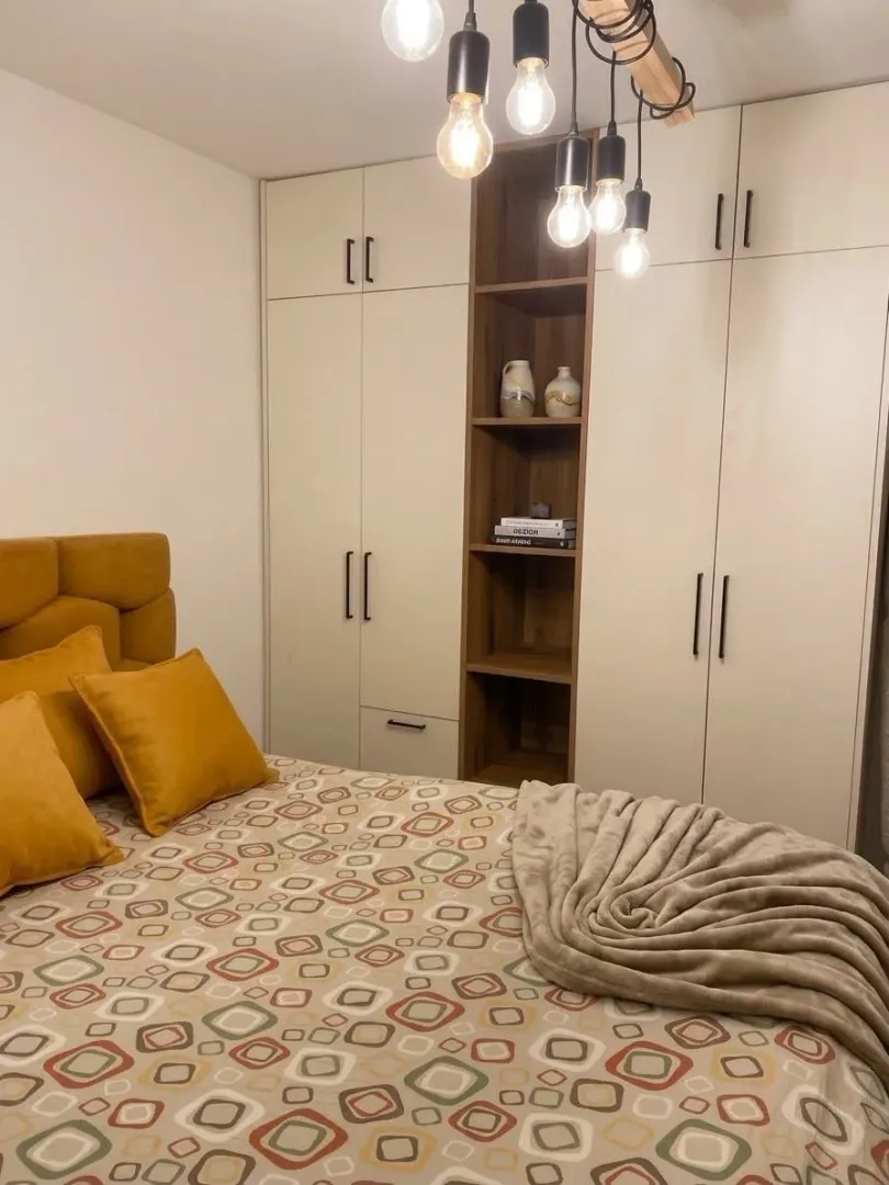 Furnished bedroom with a double bed, wardrobe, and modern lighting.