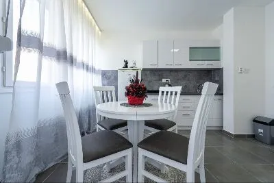 Modern kitchen with white cabinetry and a dining table. - image 2
