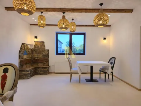 Prostrana trpezarija sa trpezarijskim stolom, unikatnim lusterima i kamenim detaljima na zidu. - image 19