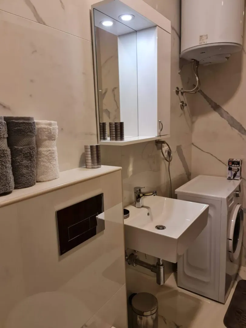 Modernly equipped bathroom with a washbasin, mirror, and washing machine.