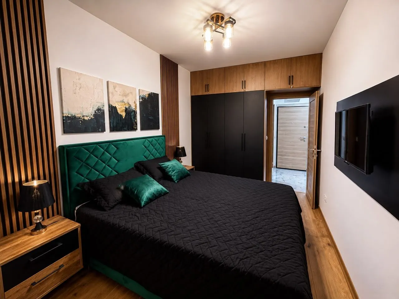 Modern bedroom with a double bed, wooden wall panels, and built-in wardrobes.