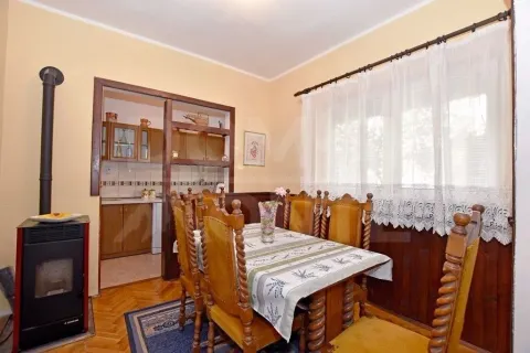 Trpezarija sa drvenim stolom i stolicama, uz peć na drva i pogled na kuhinju. - image 7