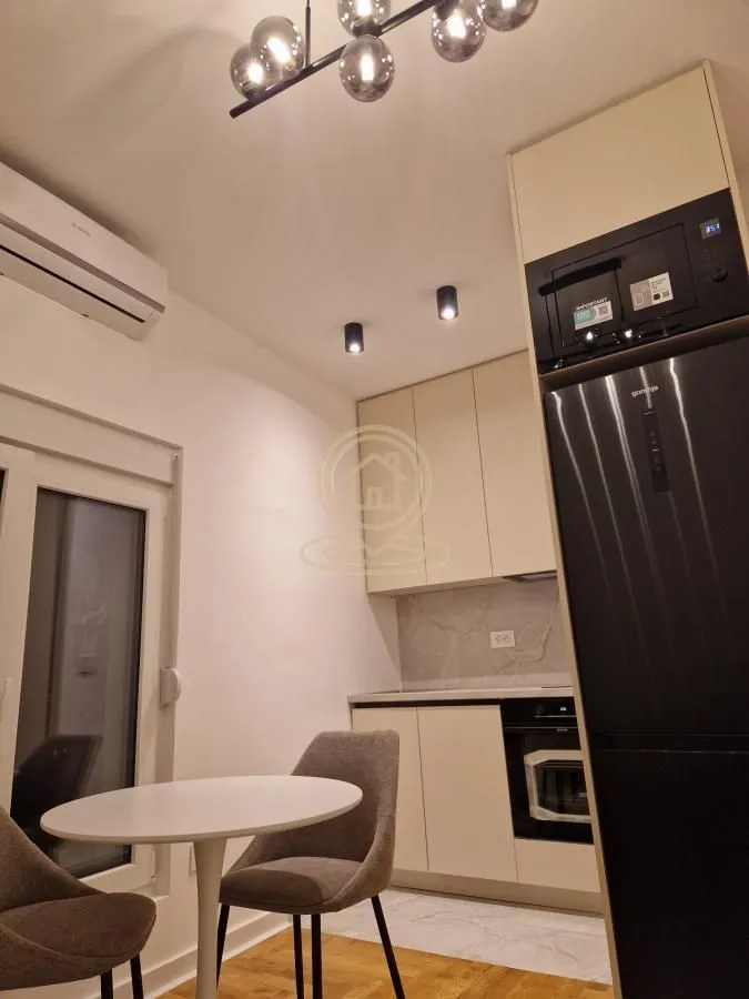 Moderna kuhinja sa ugradnim aparatima i trpezarijskim stolom sa stolicama.