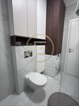 Savremeno opremljeno kupatilo sa ugradnim ormarićima, toaletom i veš mašinom. - image 10