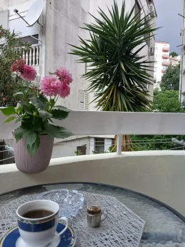 View from the terrace on surrounding buildings and greenery with a small table and flowers. - image 13