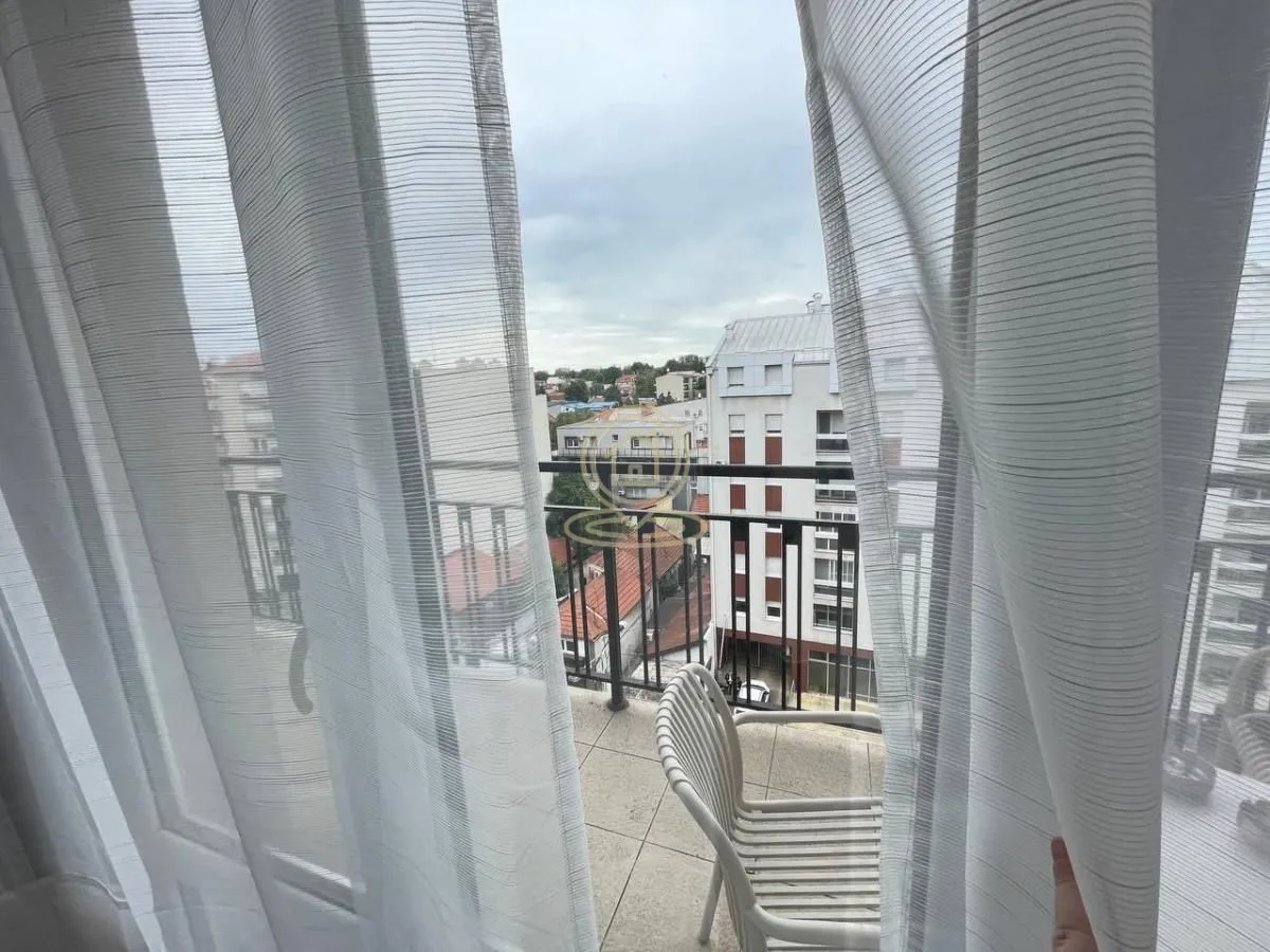 City view from the balcony through white curtains.
