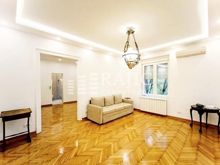 Spacious bright living room with a sofa and wooden parquet flooring.