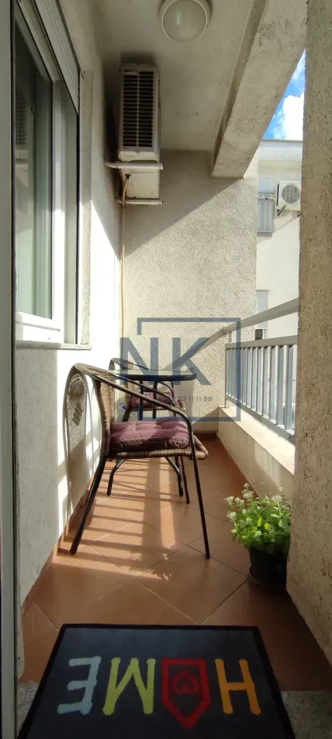 Manji natkriveni balkon sa stolom i dvije stolice.