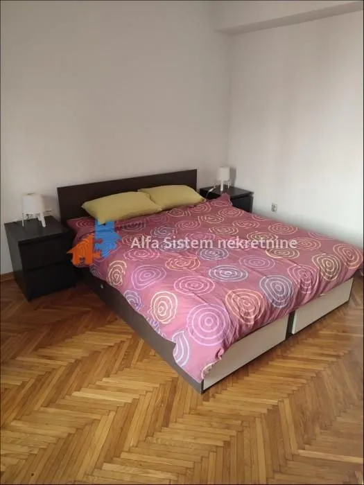 Spavaća soba sa bračnim krevetom i noćnim stočićima.