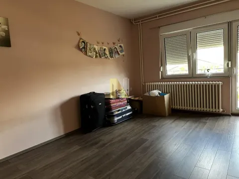 Pogled na dio praznije prostorije sa prozorom, radijatorom i koferima na podu. - image 10