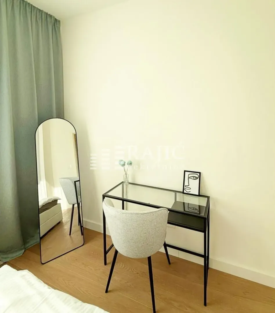 Modern bedroom with a desk, chair, and floor mirror.