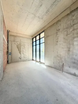 Empty room in gray phase of construction with a large window. - image 3