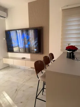 Dnevni boravak sa montiranim televizorom i šankom sa barskim stolicama. - image 4