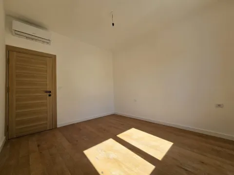 Empty room with wooden flooring, white walls, and an air conditioning unit. - image 8