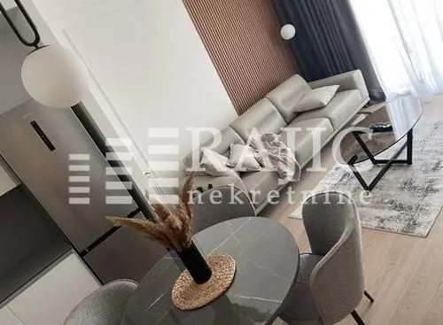 Living room with a sofa, dining table, and kitchen in the background.
