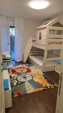 Children's bedroom with a bunk bed, desk, and colorful rug. - image 11