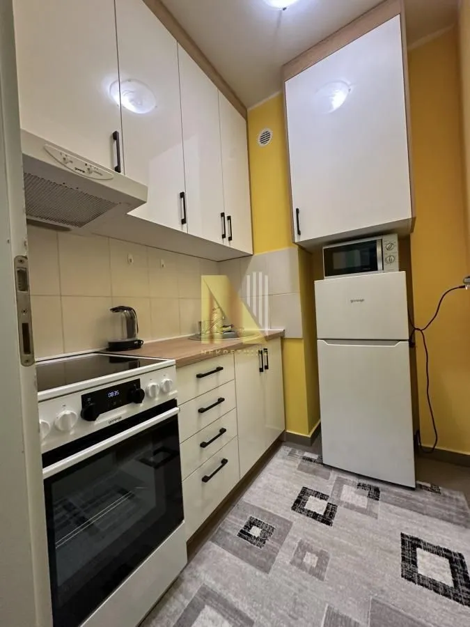 Manja opremljena kuhinja sa belim elementima i šporetom.