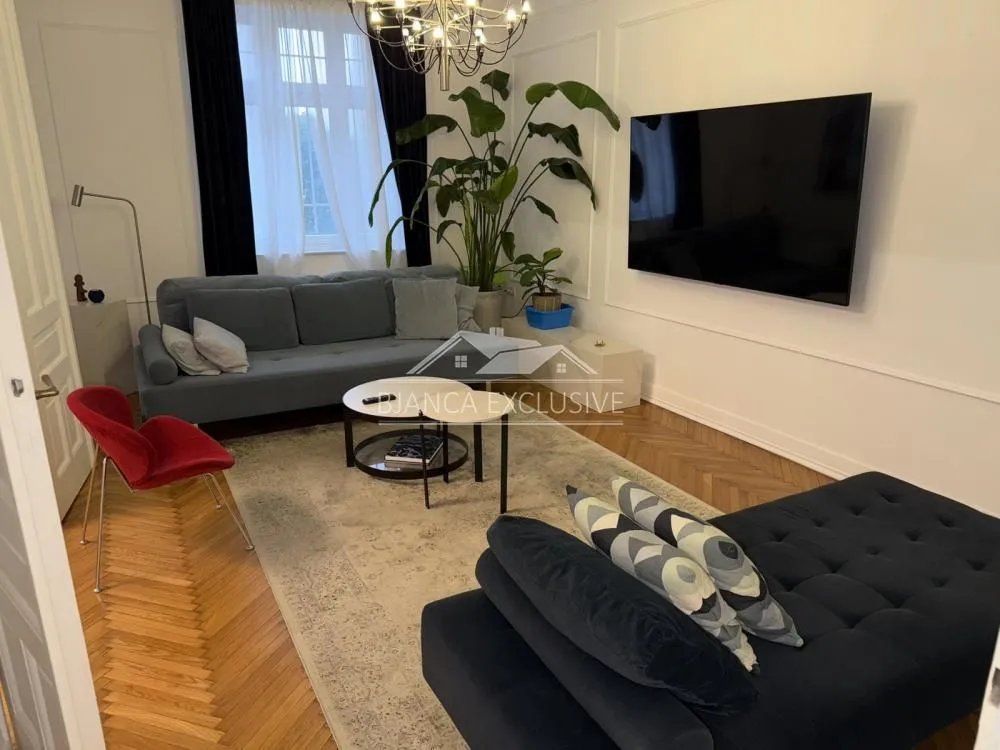 Udobna dnevna soba sa garniturom, televizorom i ukrasnim biljkama.