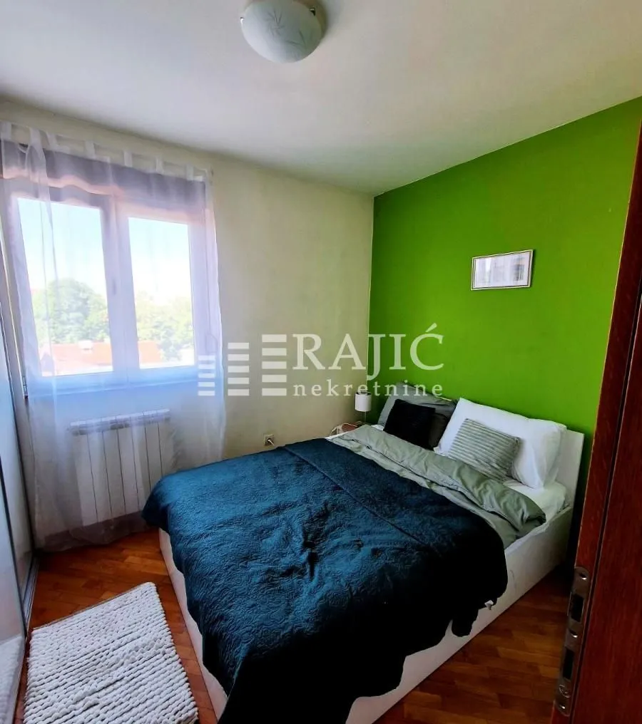 Furnished bedroom with a double bed and a green accent wall.