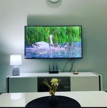 Dnevna soba sa televizorom na zidu i komodom. - image 2