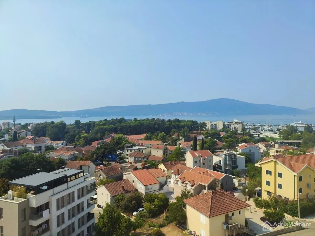 Pogled sa prozora na naselje, grad i more u daljini.