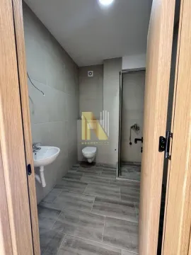 Pogled iz hodnika na novije opremljeno kupatilo sa tuš kabinom. - image 7
