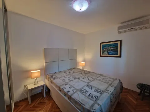 Spavaća soba sa bračnim krevetom, noćnim stočićima i umetničkom slikom na zidu. - image 3