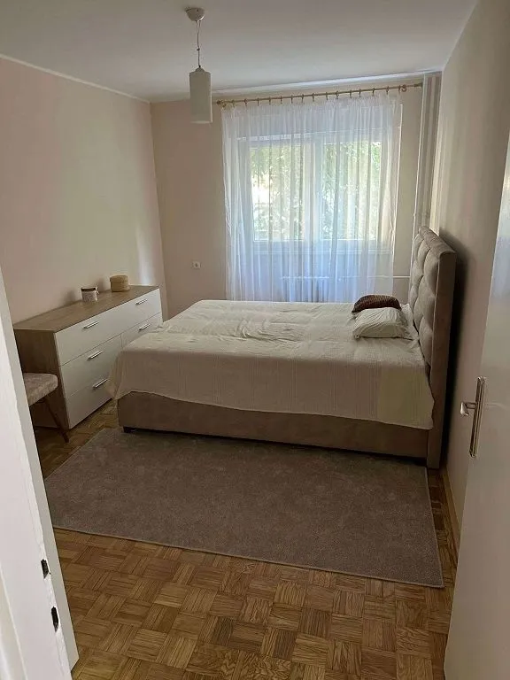 Nameštena spavaća soba sa bračnim krevetom i komodom.
