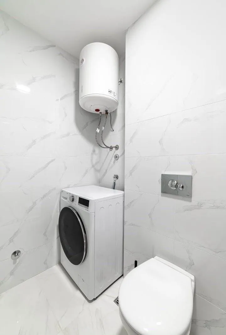 Moderno opremljeno kupatilo sa veš mašinom i ugradnim bojlerom.