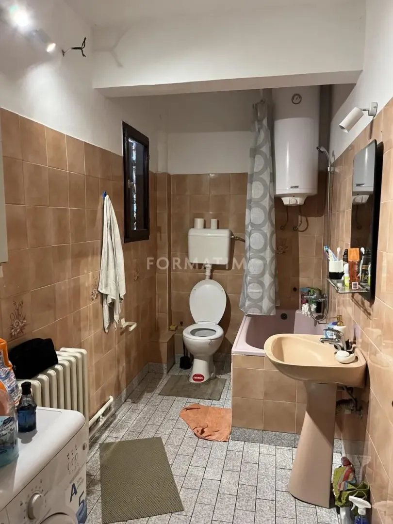 Bathroom equipped with sanitary fixtures, a bathtub, and a water heater with brown tiles.