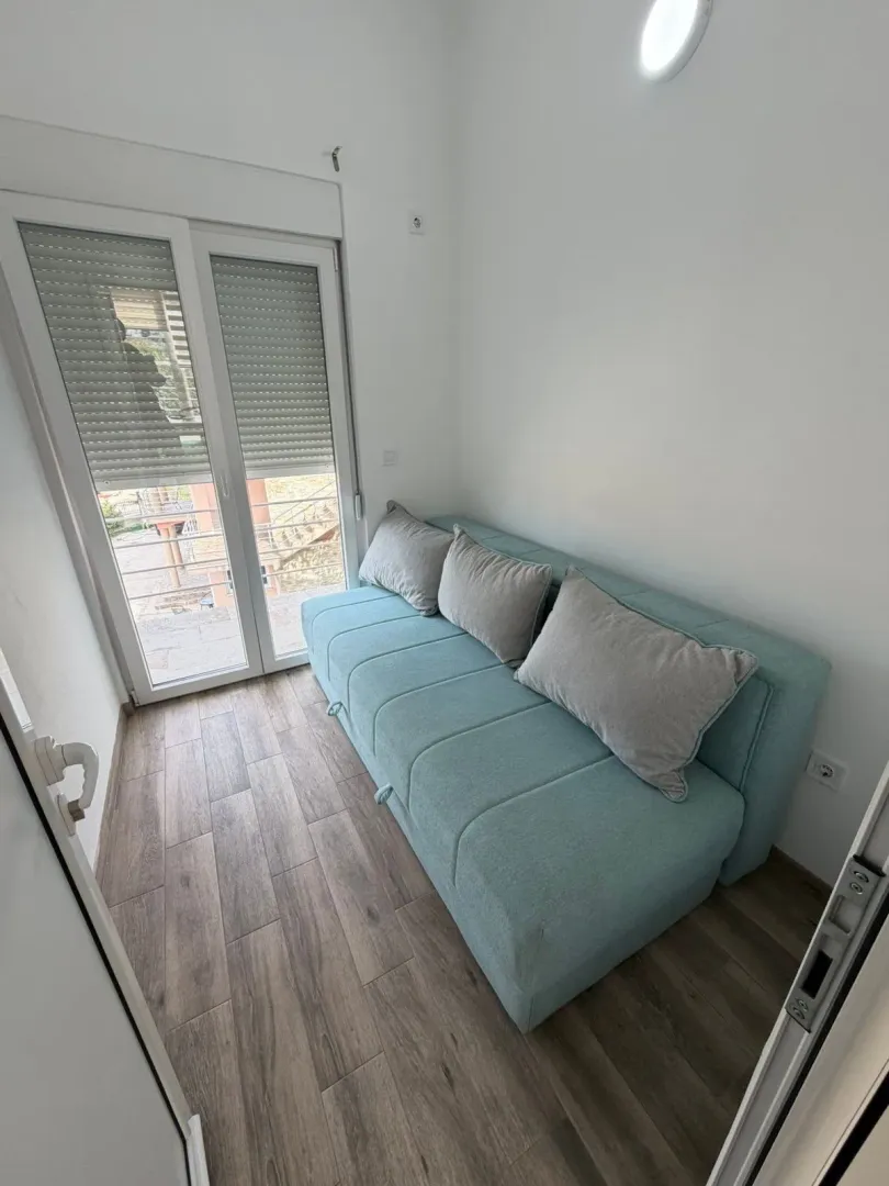 Smaller living room with a turquoise pull-out sofa and access to the terrace.