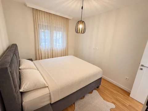Furnished bedroom with a double bed, window, and hanging lamp. - image 3