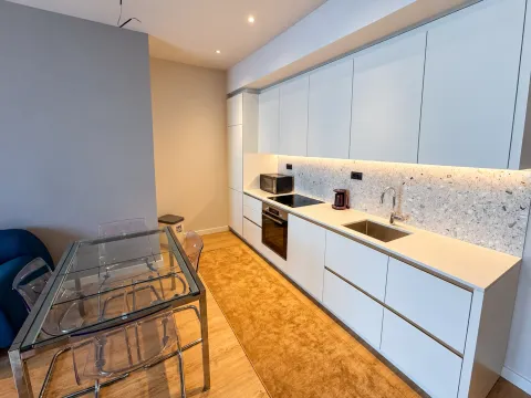 Moderna kuhinja sa bijelim elementima i trpezarijskim stolom. - image 3