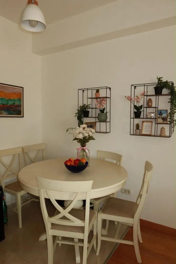 Trpezarija sa okruglim stolom, stolicama i ukrasnim policama na zidu.