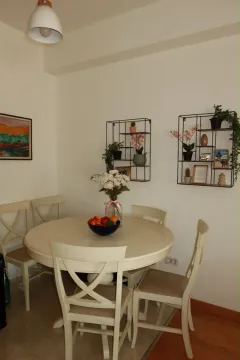 Trpezarija sa okruglim stolom, stolicama i ukrasnim policama na zidu. - image 5